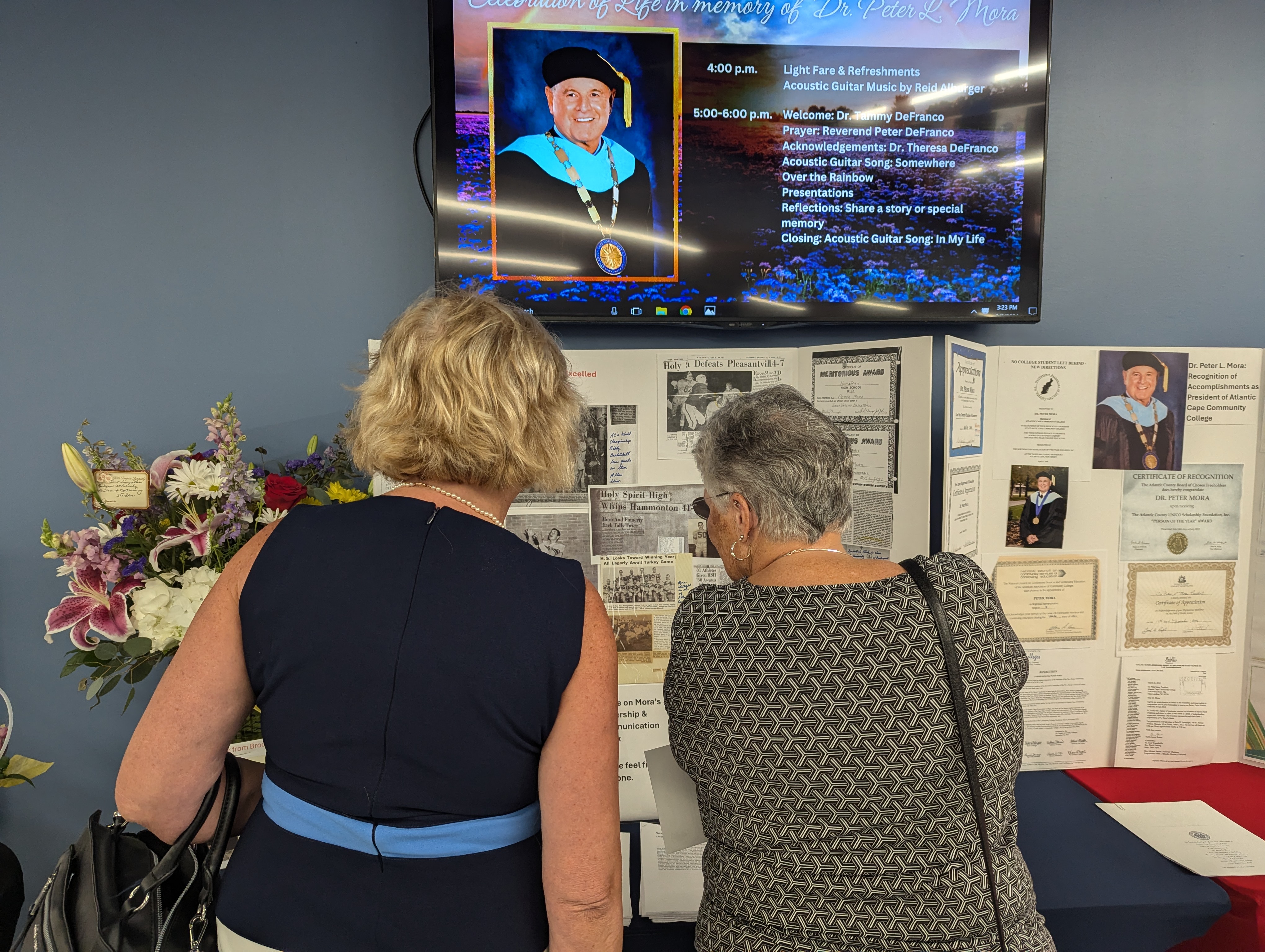 Guests glance at photos of the late Dr Peter Mora