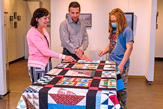 three people view a piece of artwork