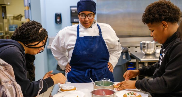 Member of the Academy of Culinary Arts with summer camp students in culinary kitchen